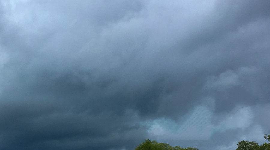 The boiling dark clouds of a thunderstorm head towards a small country road on an early summer afternoon.