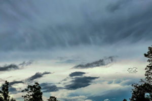 Fluffy cirrus clouds float in front of the dark clouds of an approaching thunderstorm in north central Florida.