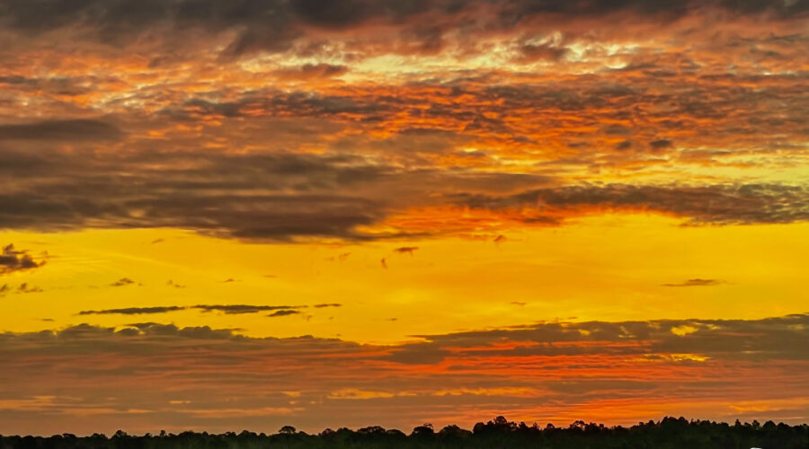 Color from the rising sun spreads along the overhanging clouds as it begins to light up a new day.