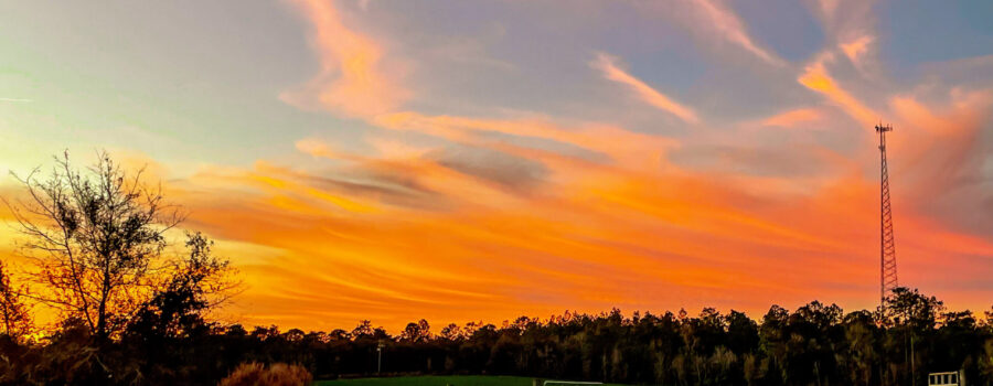 A fiery sunset lights up the overhead clouds in bright hues of orange and yellow.