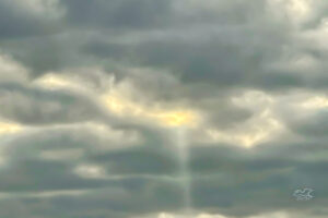 A single beam of light shines through the clouds like a message from above.