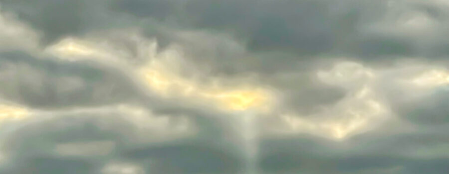 A single beam of light shines through the clouds like a message from above.