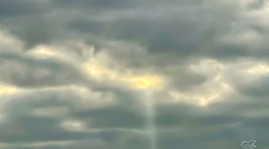 A single beam of light shines through the clouds like a message from above.