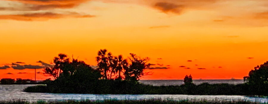 A beautiful orange sunset occurs over an offshore island in central Florida.