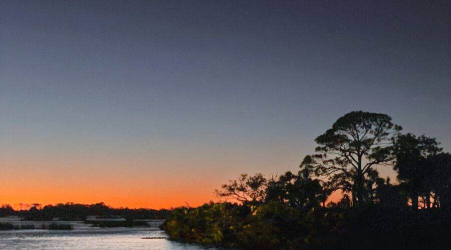 The sun sets behind a small island just of the shore of Cedar Key, Florida.